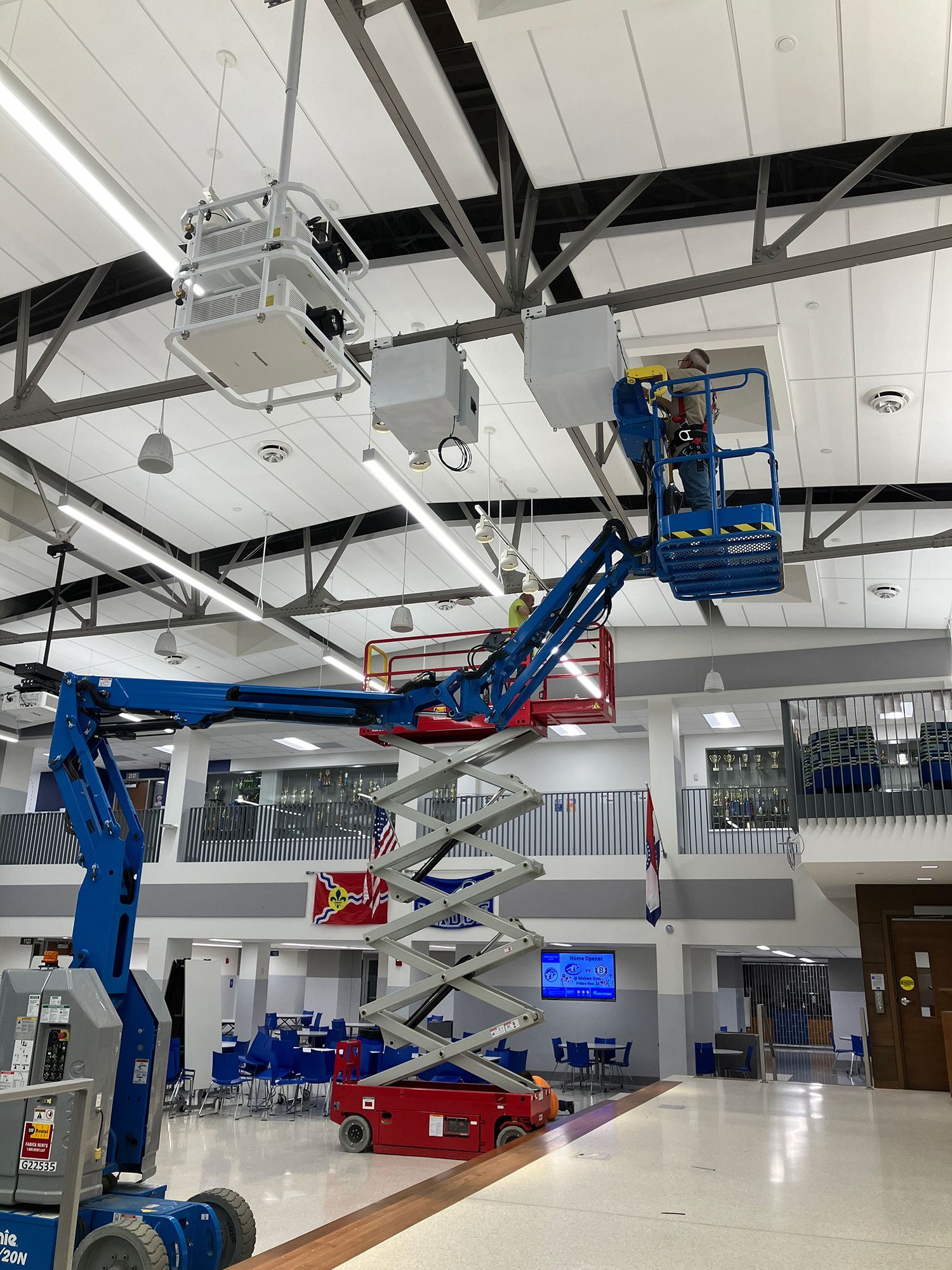 A man is working on a scissor lift in a large building.
