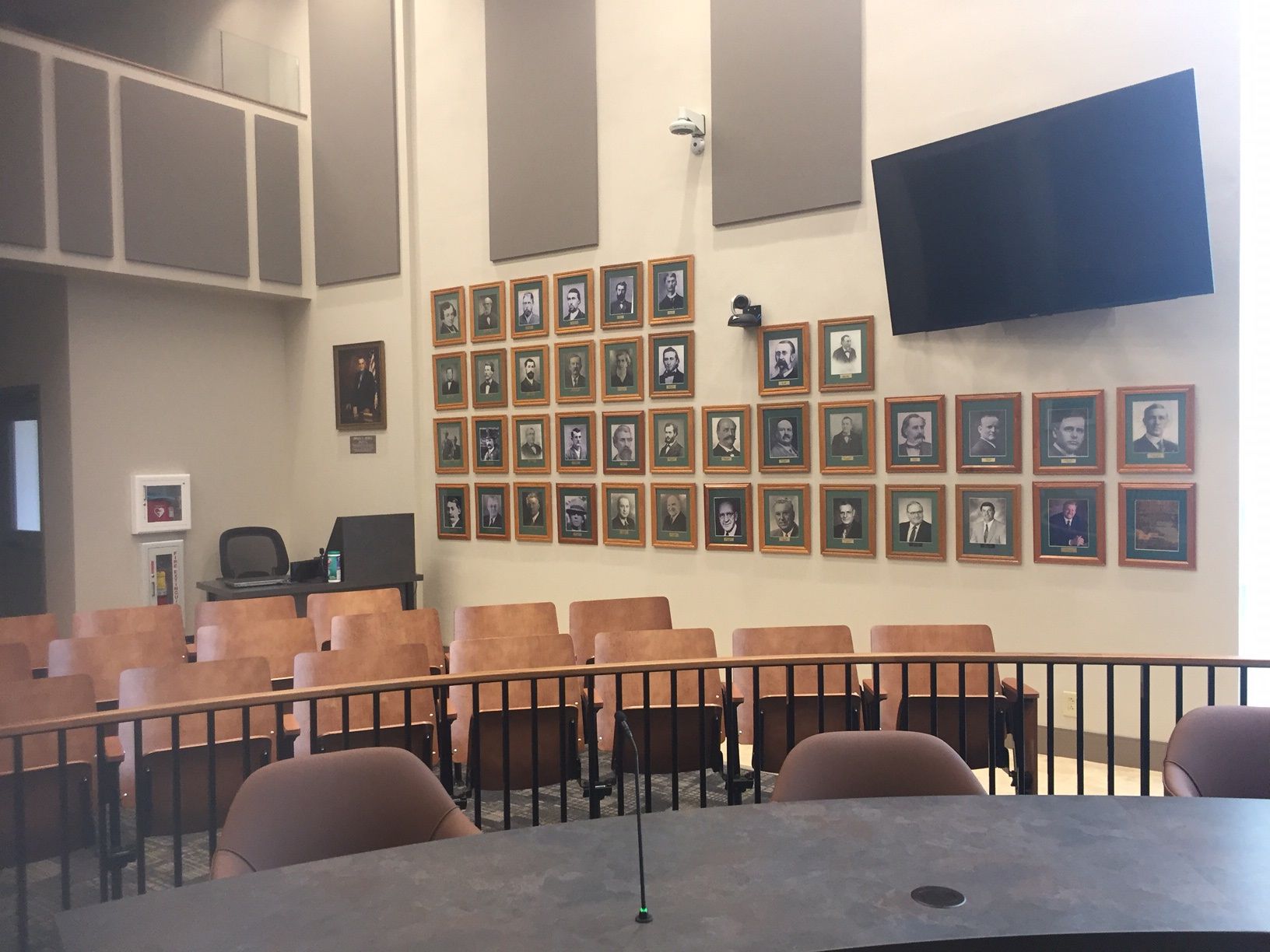 A classroom with rows of chairs and a tv on the wall