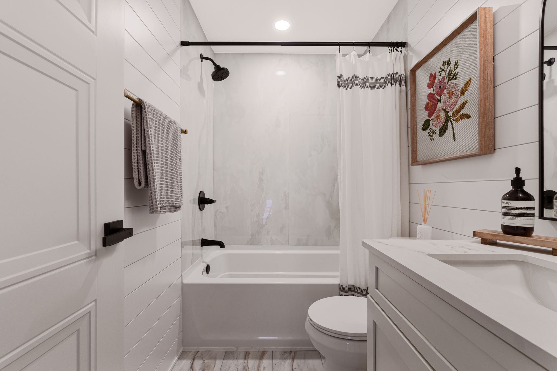 Bright white modern bathroom with tub, shower, vanity, and wall art