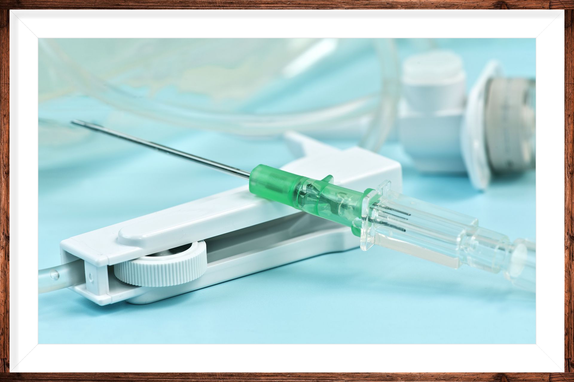 IV catheter with needle and tubing on a light blue surface. A white roller clamp is also in the foreground.