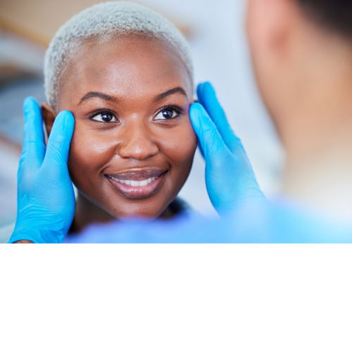 A person's face being examined by a person wearing blue gloves, indoors.