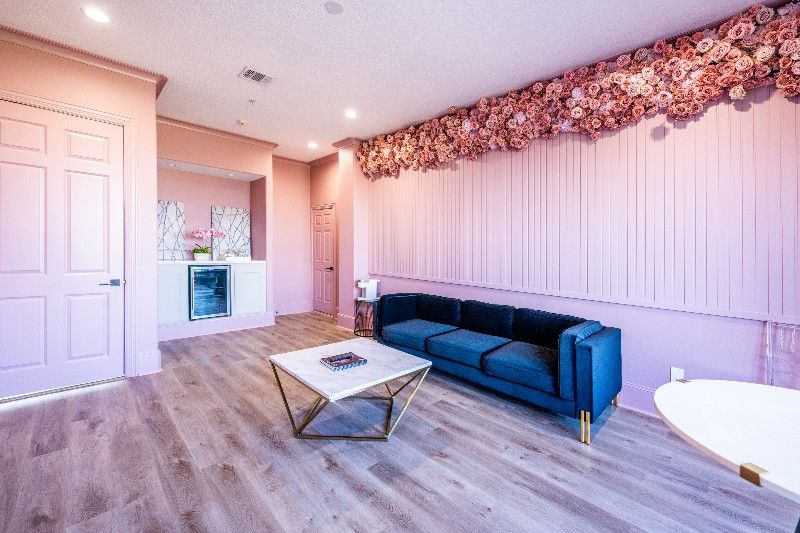 A living room with a blue couch , coffee table , and pink walls.