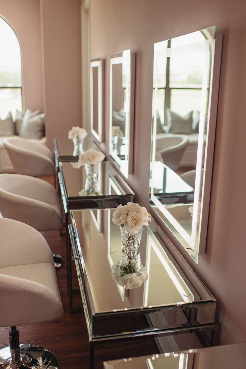 A row of chairs in a salon with mirrors and vases of flowers.