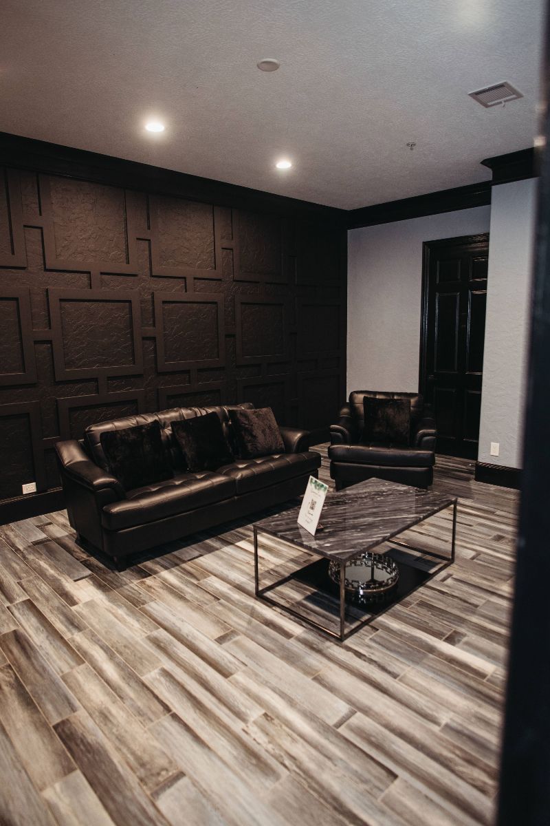 A living room with a couch , chair , coffee table and black walls.