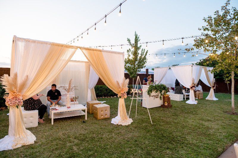 A man is sitting under a canopy in a backyard.
