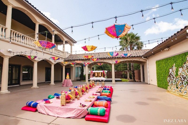 A long table with umbrellas hanging from the ceiling in a courtyard.