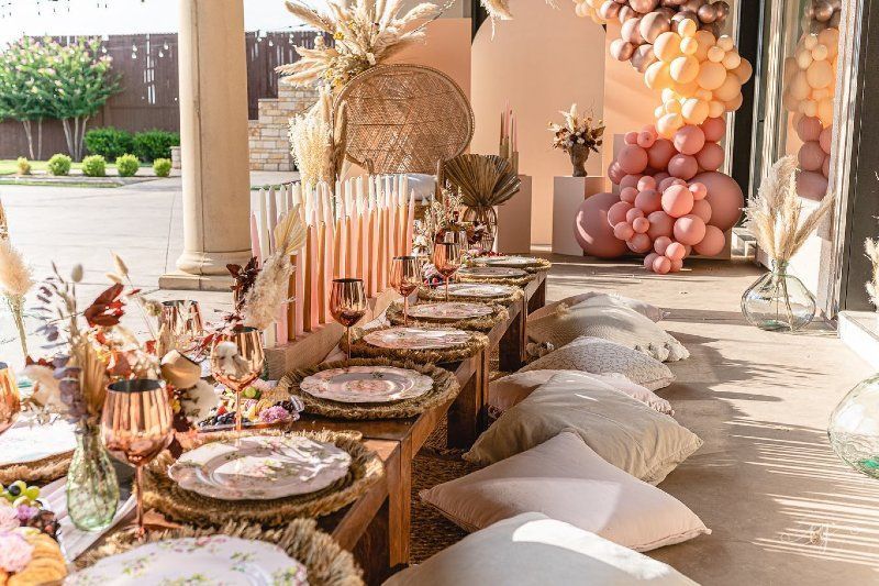 A table set up for a party with plates , glasses , and pillows.