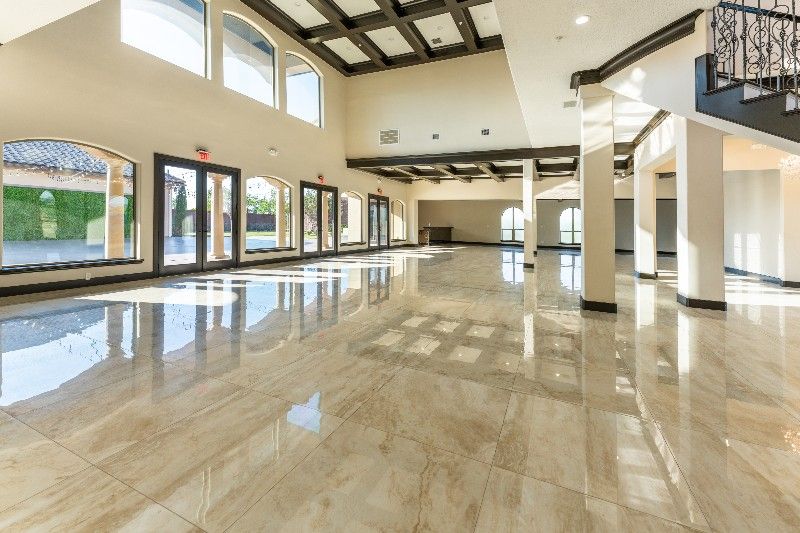 A large empty room with a marble floor and lots of windows.