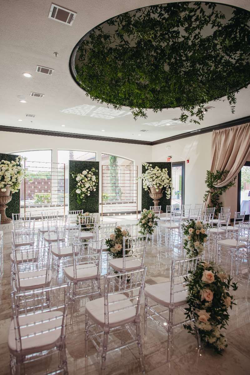 A room filled with chairs and flowers for a wedding ceremony.