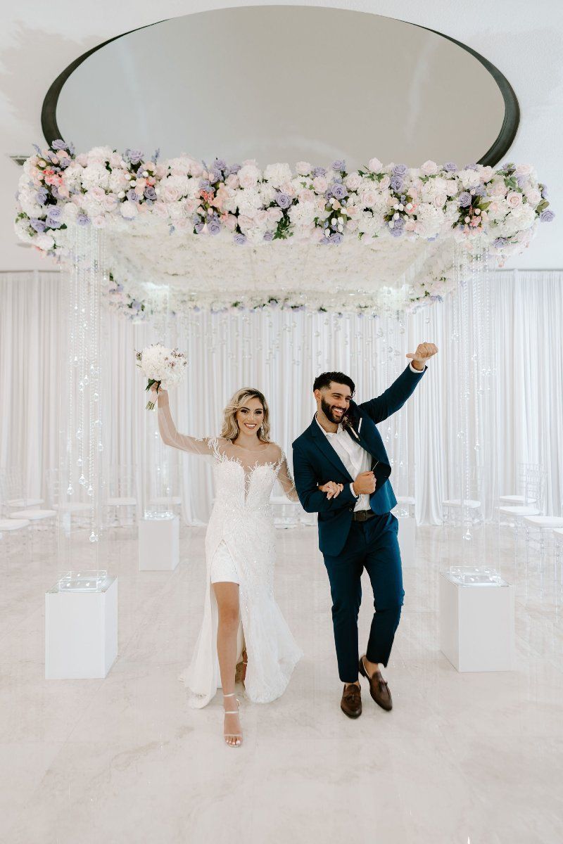 A bride and groom are dancing under a chandelier at their wedding reception.