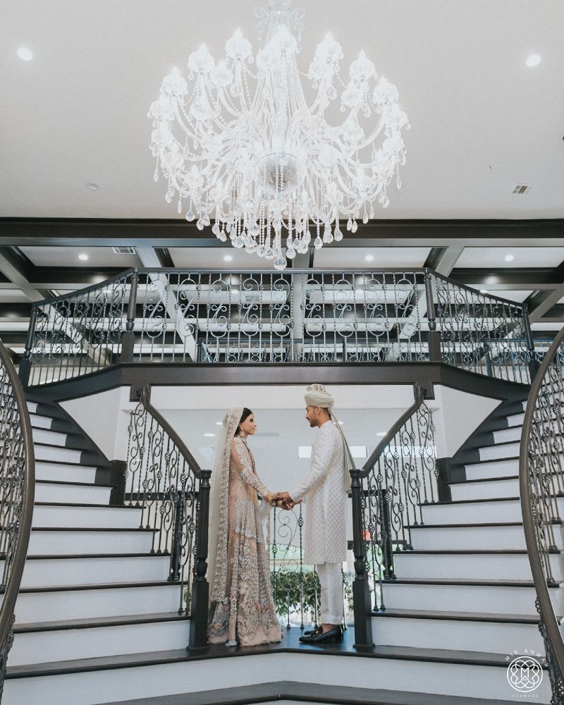 A bride and groom are standing on a set of stairs holding hands.