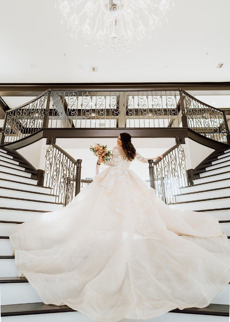A bride in a wedding dress is standing on a set of stairs.