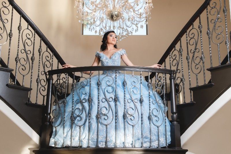 A woman in a blue dress is standing on top of a set of stairs.