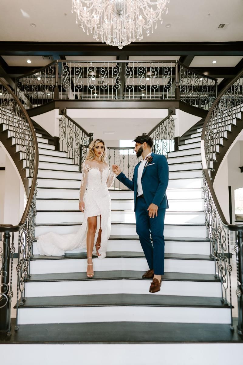 A bride and groom are walking down a set of stairs.