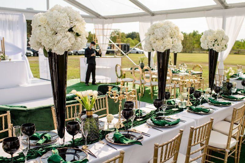 A long table with a lot of flowers on it is sitting under a tent.