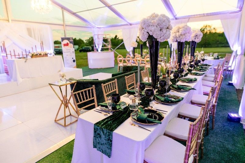 A long table is set for a wedding reception under a tent.
