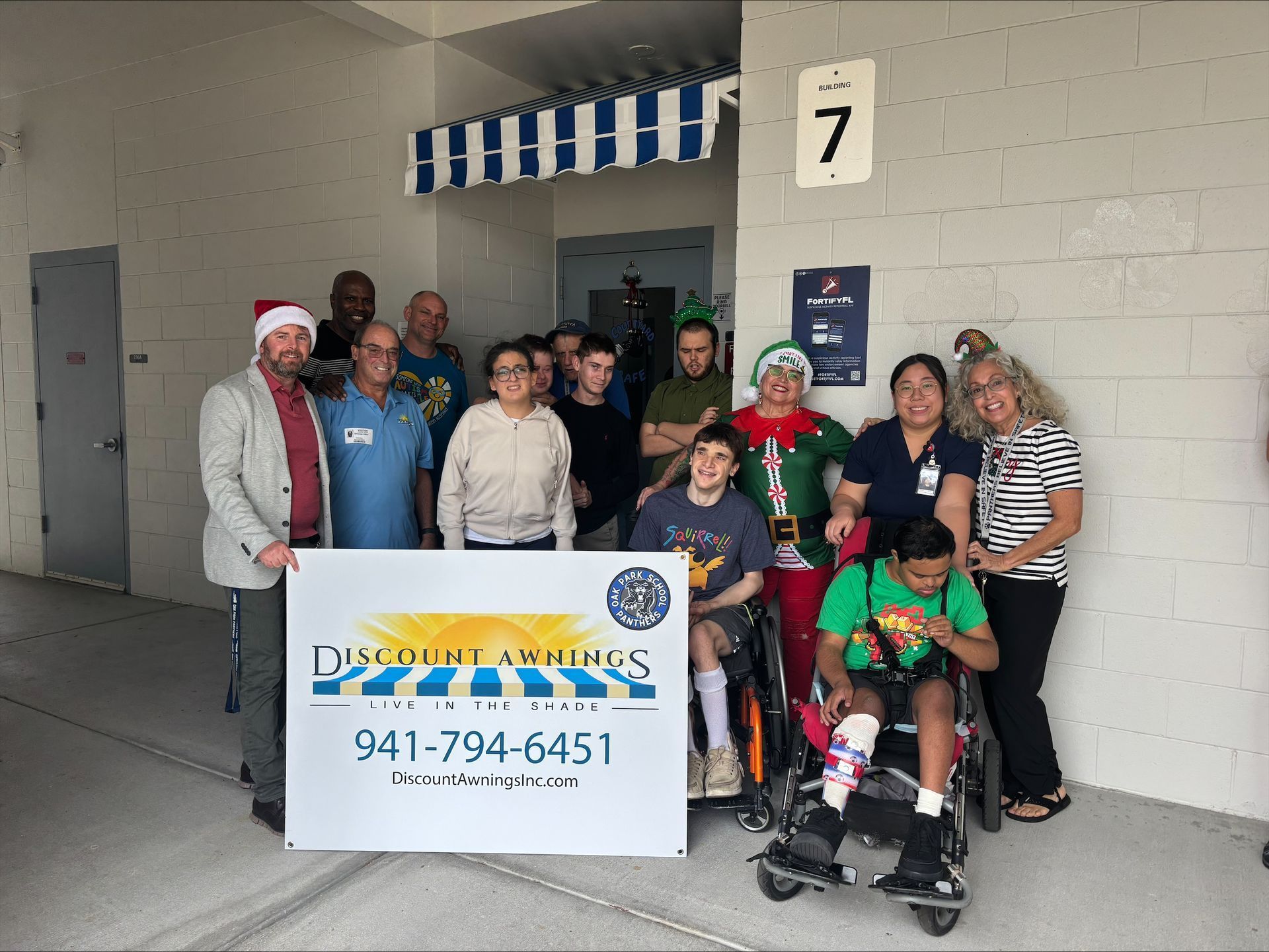 Group poses with banner for Discount Sprinklers; building exterior.