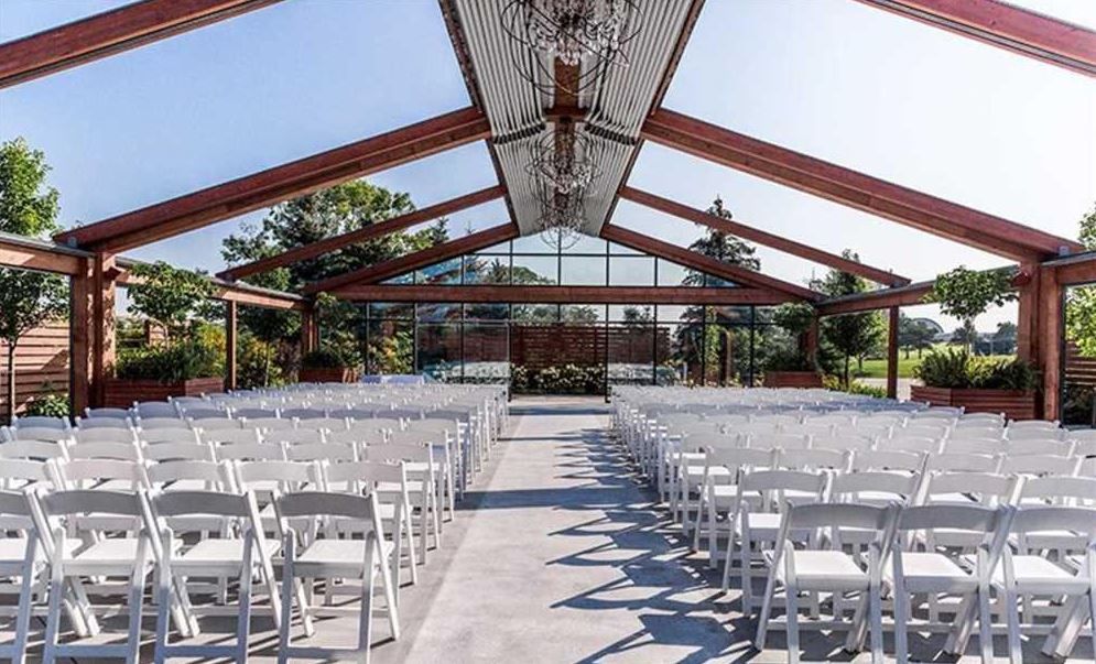 a row of white folding chairs are lined up in front of a large building