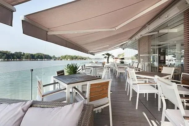 a restaurant with tables and chairs and an awning overlooking the water .
