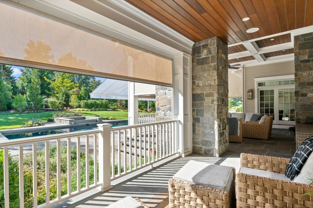 a large porch with wicker furniture and a pool in the background