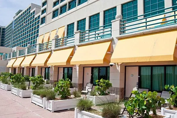 a row of hotel rooms with yellow awnings and planters in front of them .