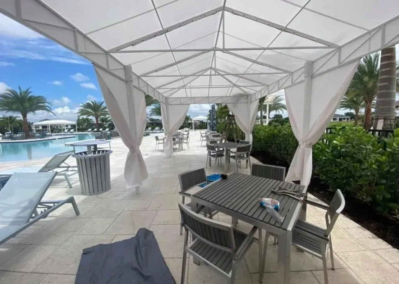 a table and chairs under a canopy next to a pool .