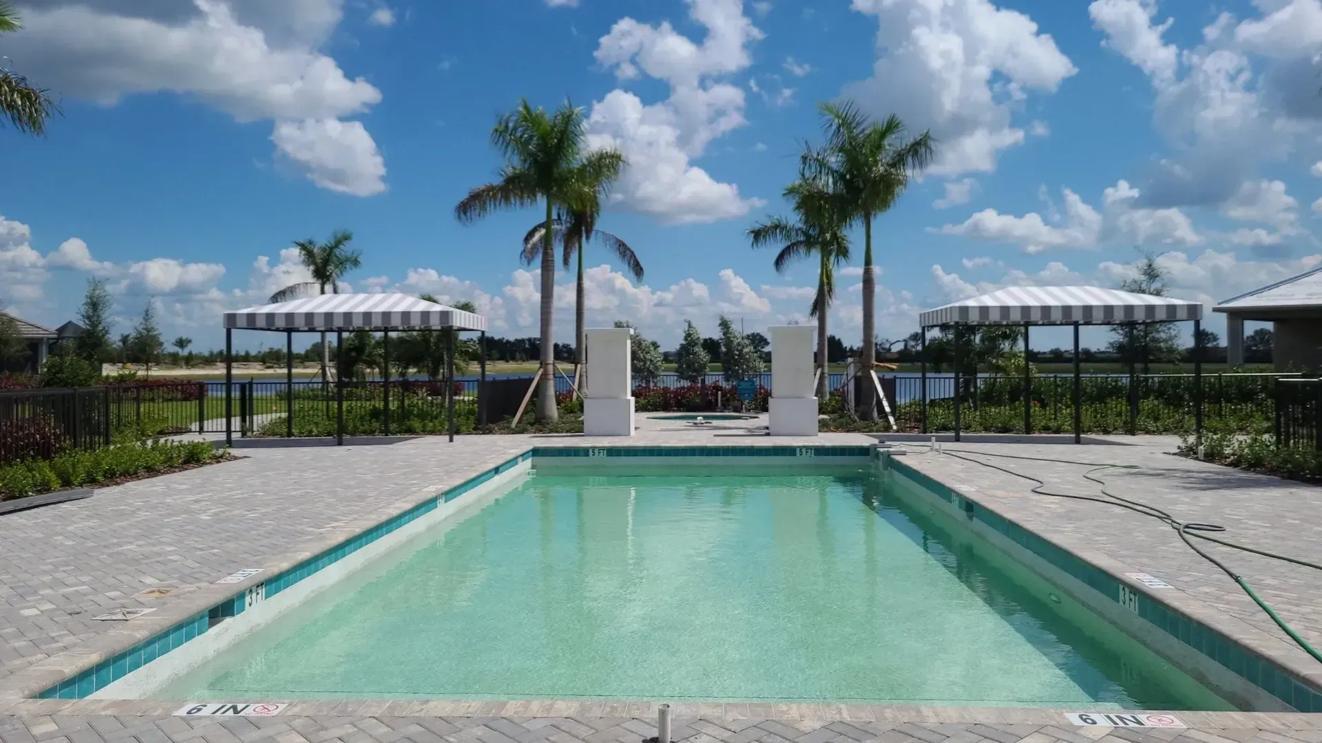 a large swimming pool surrounded by palm trees on a sunny day