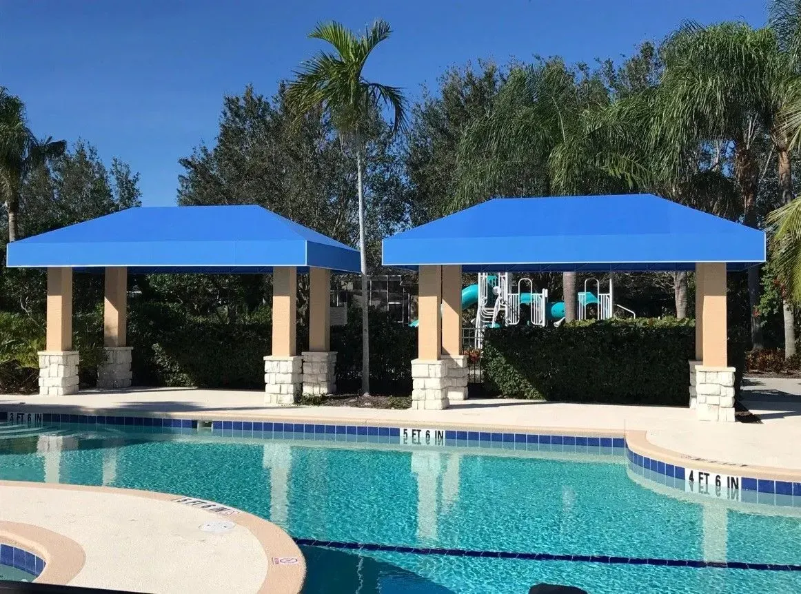 a swimming pool with two blue canopies over it