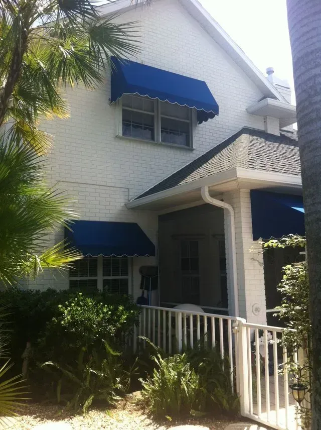 a white house with blue awnings on the windows