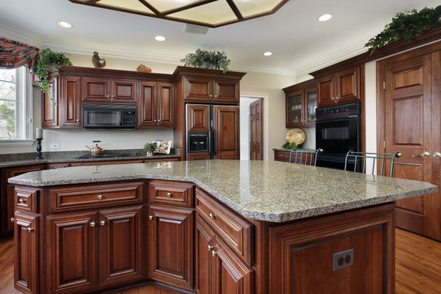 Modern kitchen with dark wood cabinets, granite island, and stainless steel appliances