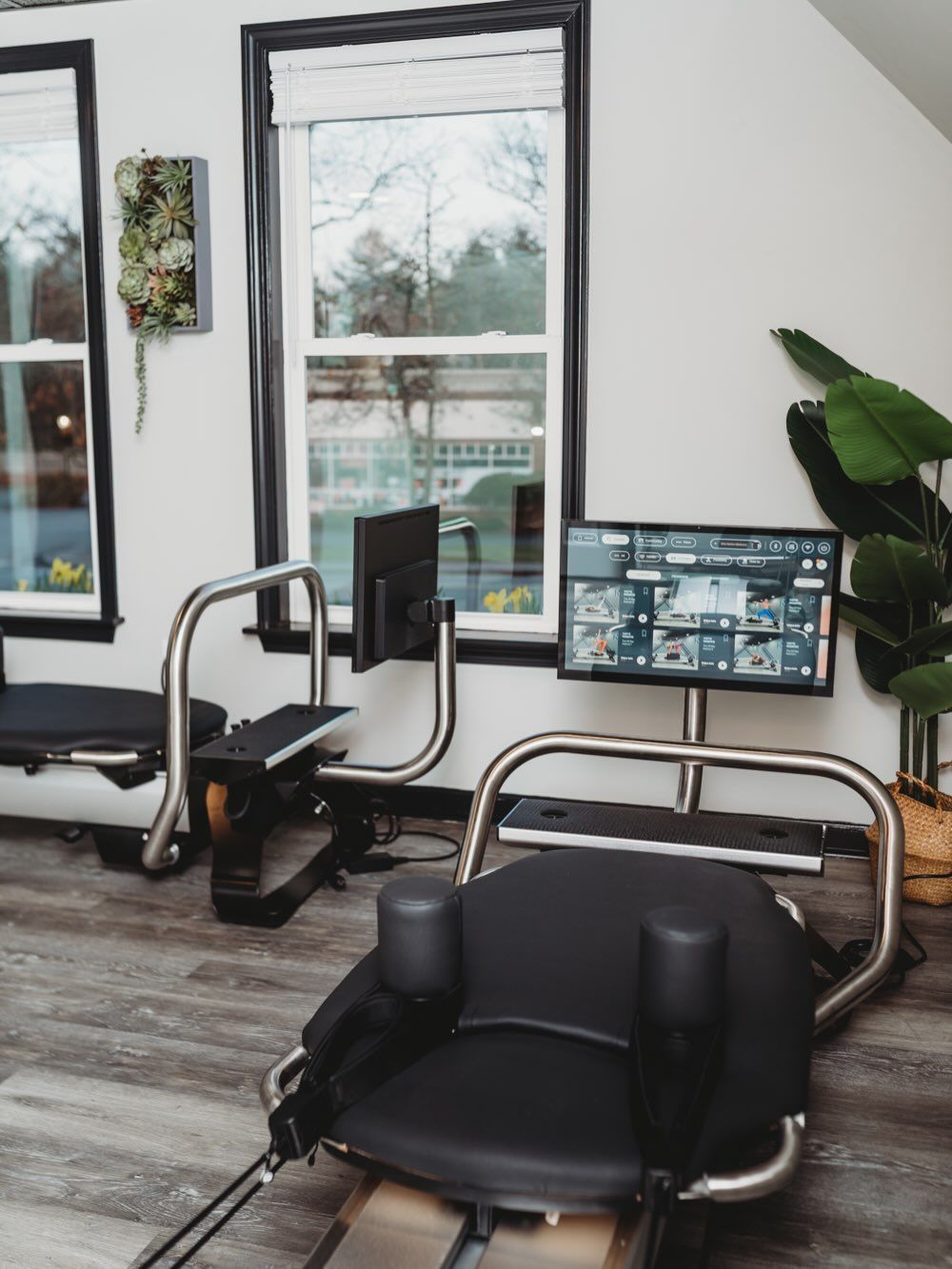 People exercising on treadmills in a modern gym, stretching with arms extended on black equipment.