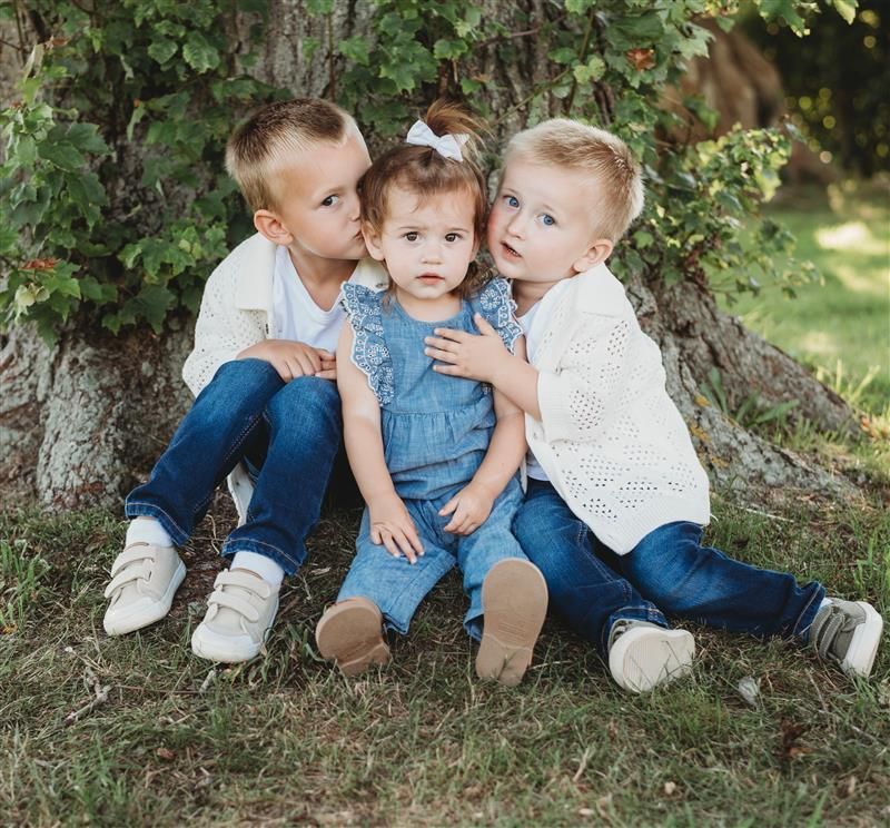 Woman in burgundy workout clothes sitting, raising arm with peace sign.