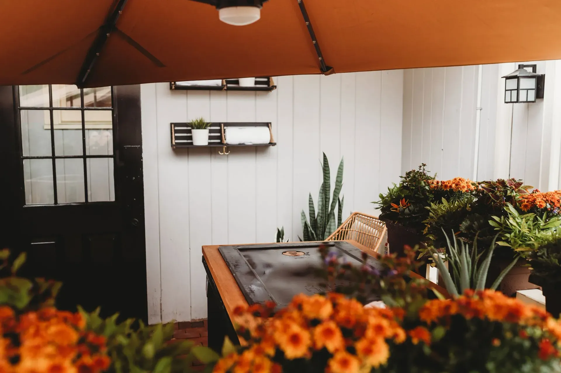 Outdoor floral display with orange flowers, plants, and an umbrella.