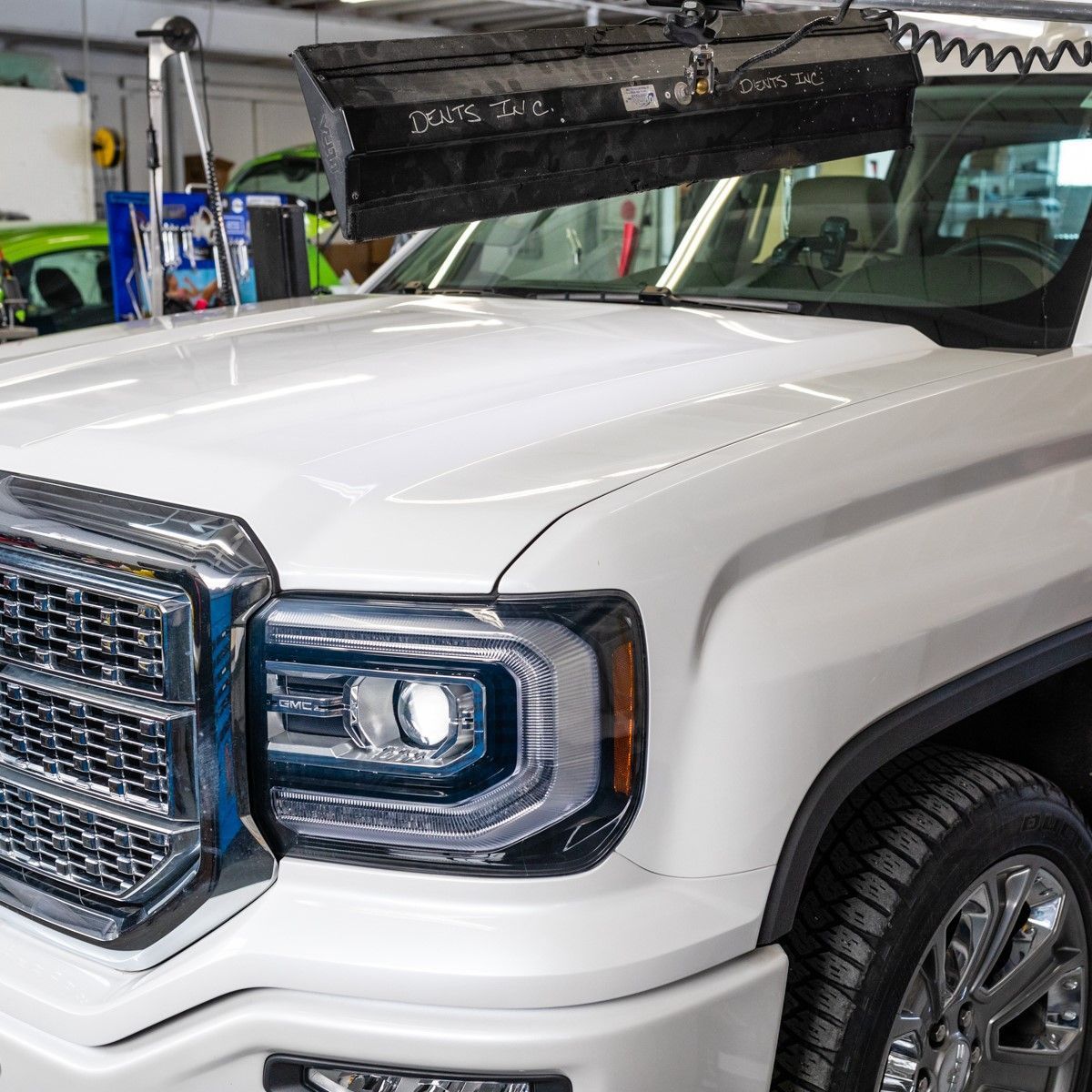 White pickup truck front end in a garage, with a raised hood and chrome grille