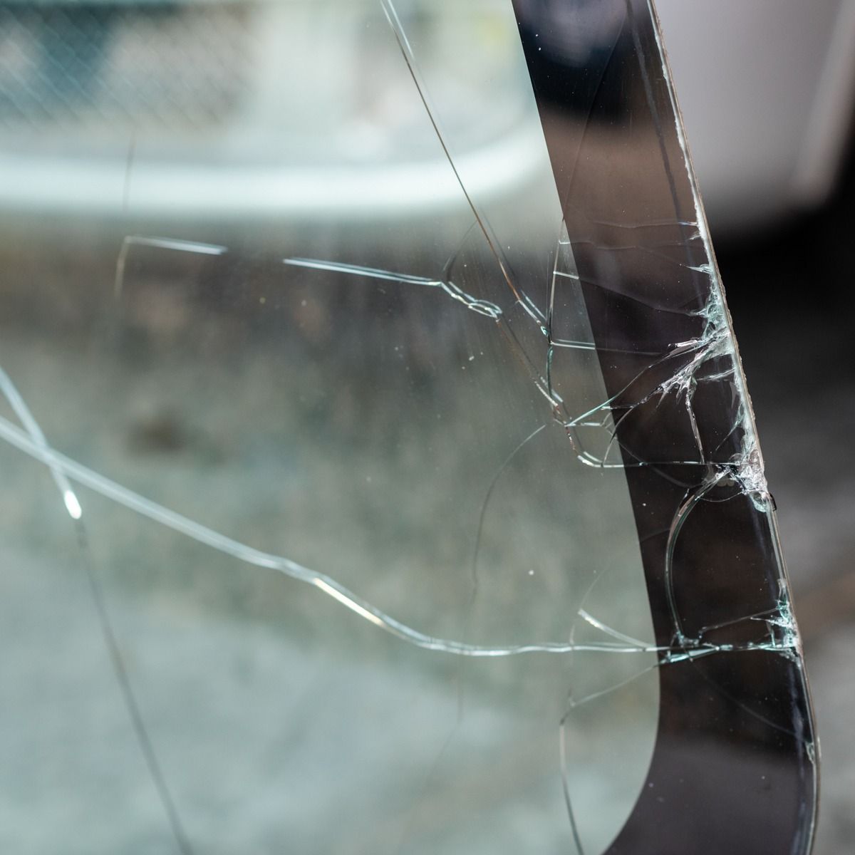 Cracked glass with spiderweb fractures on a reflective black surface