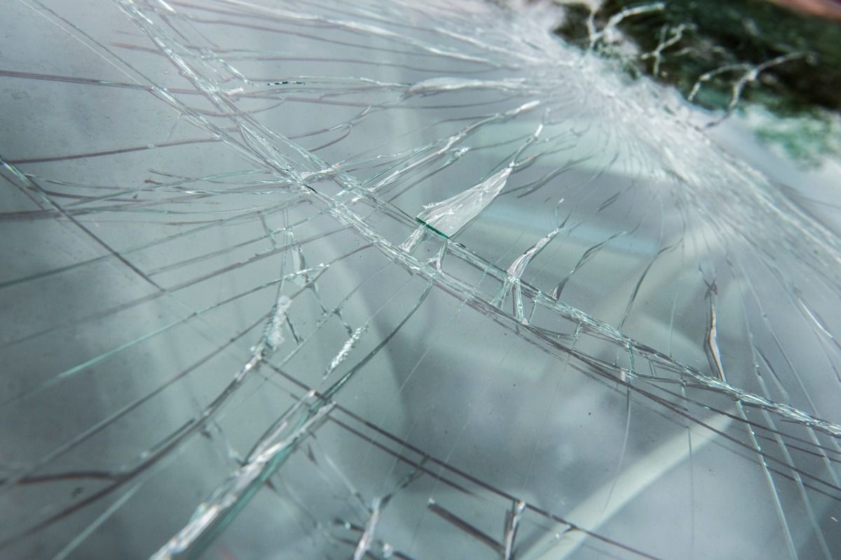 Cracked glass with spiderweb fractures on a pale blue surface