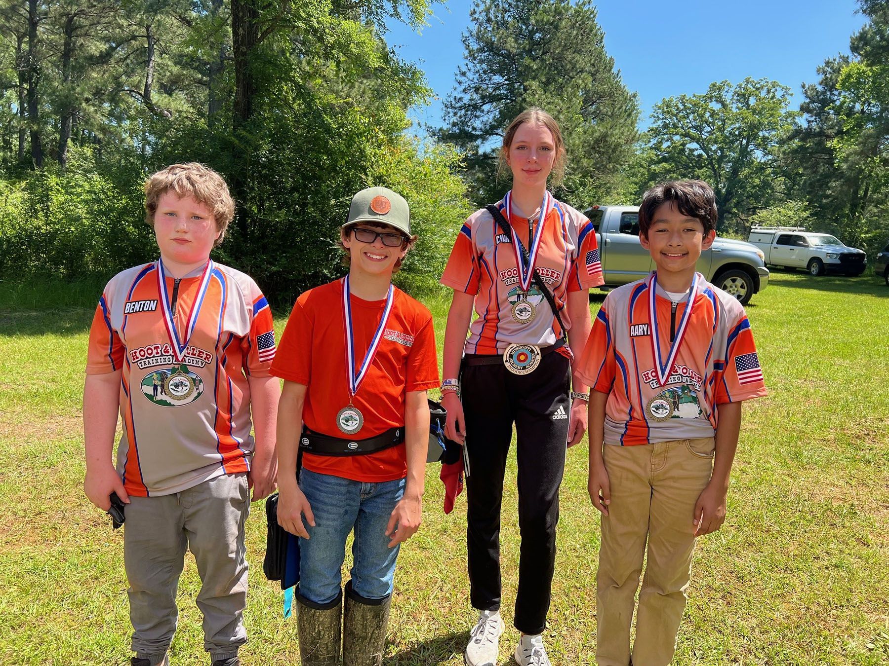 A group of young people wearing medals are standing in a field.