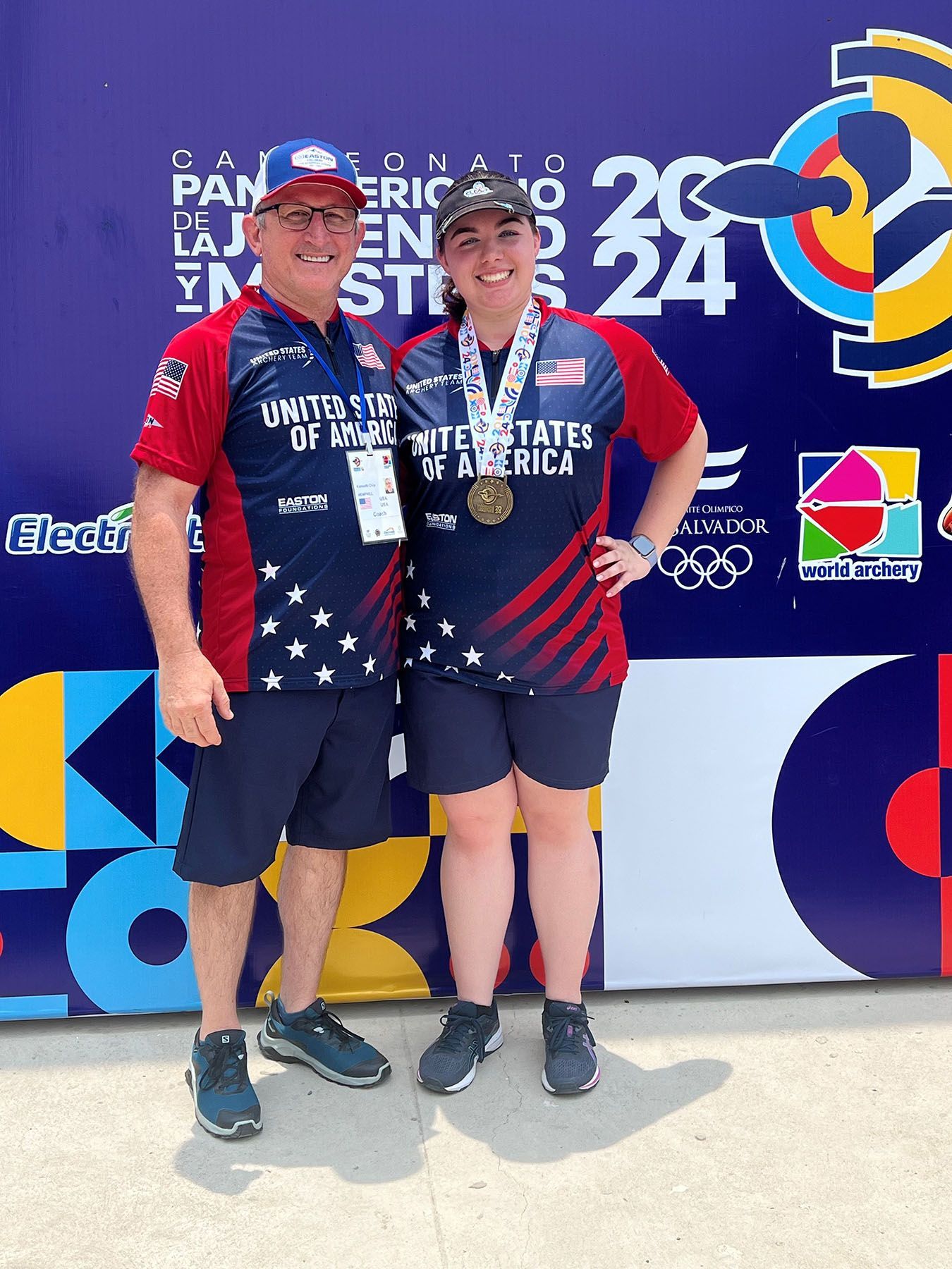 A man and a woman are posing for a picture in front of a purple wall.
