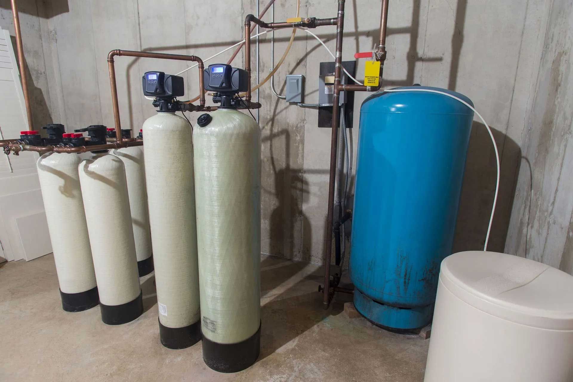 Water filtration system with multiple tanks and copper pipes in a basement.