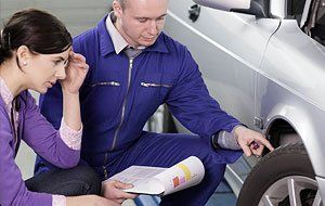 Mechanic looking at a car with a customer