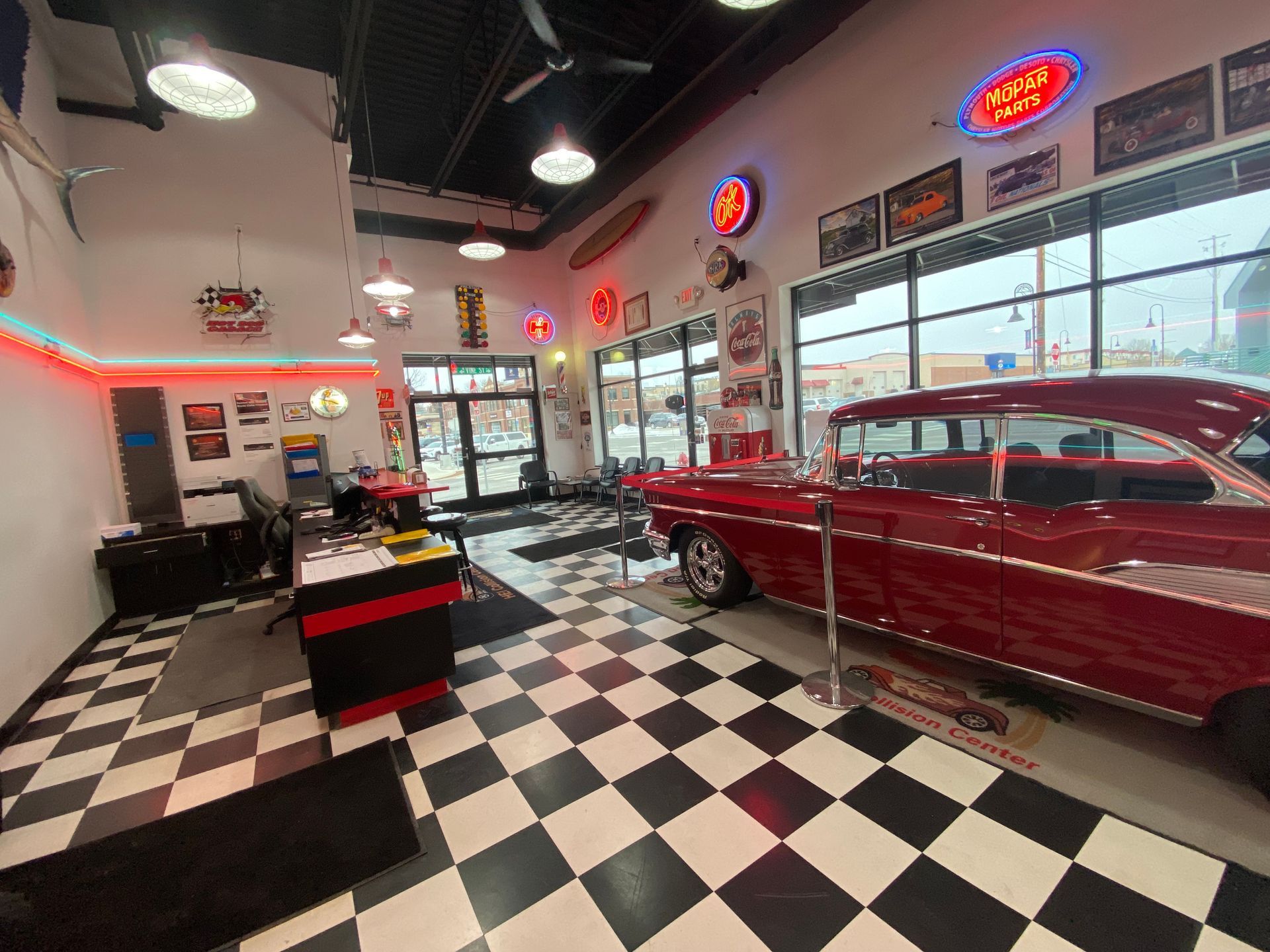 A red car is parked in a garage with a checkered floor.