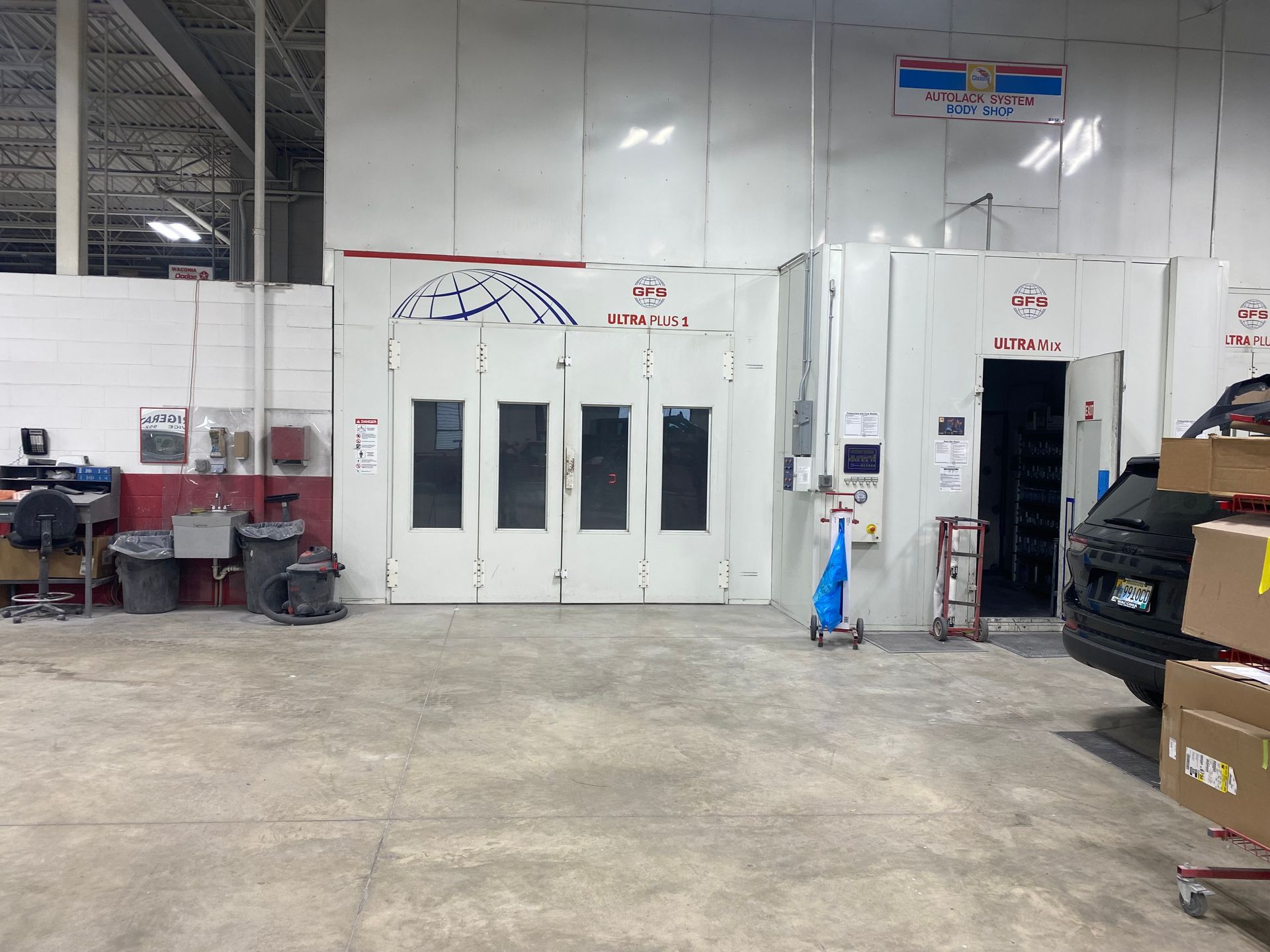 A car is parked in a garage next to a paint booth.