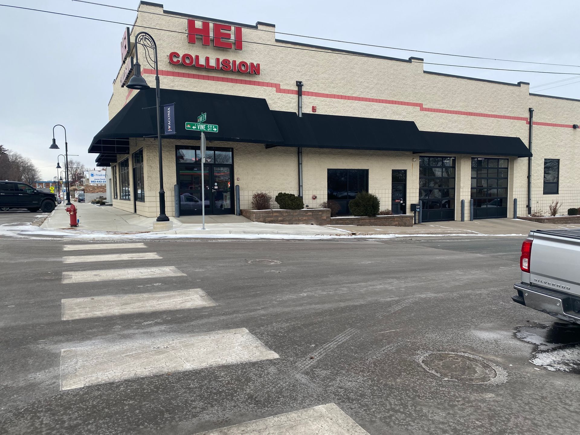A truck is parked in front of a collision repair shop.