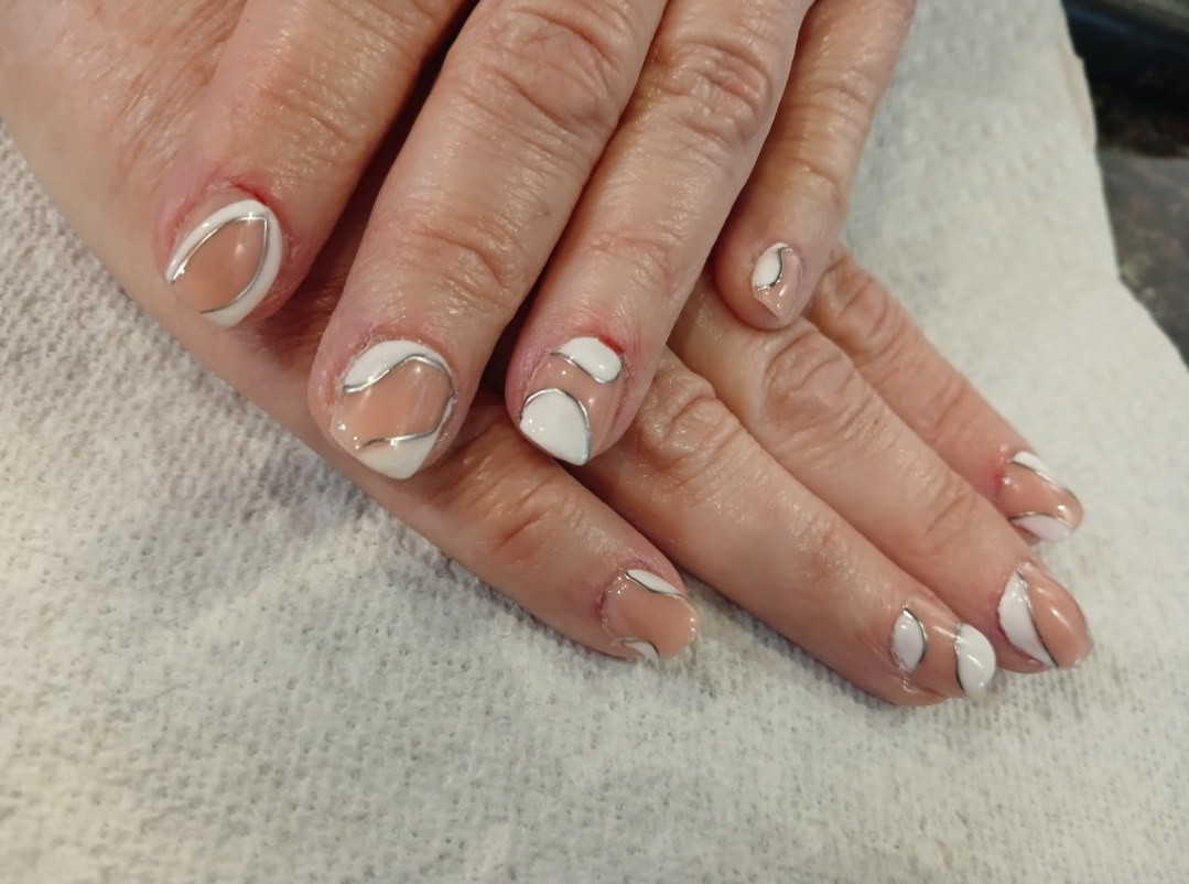 Hands with nude nails, white curved designs.