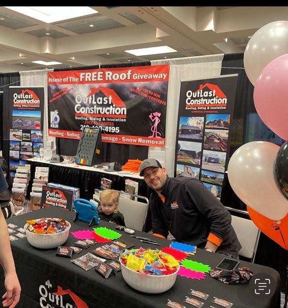 A man standing in front of a table with balloons and a sign that says outlast construction