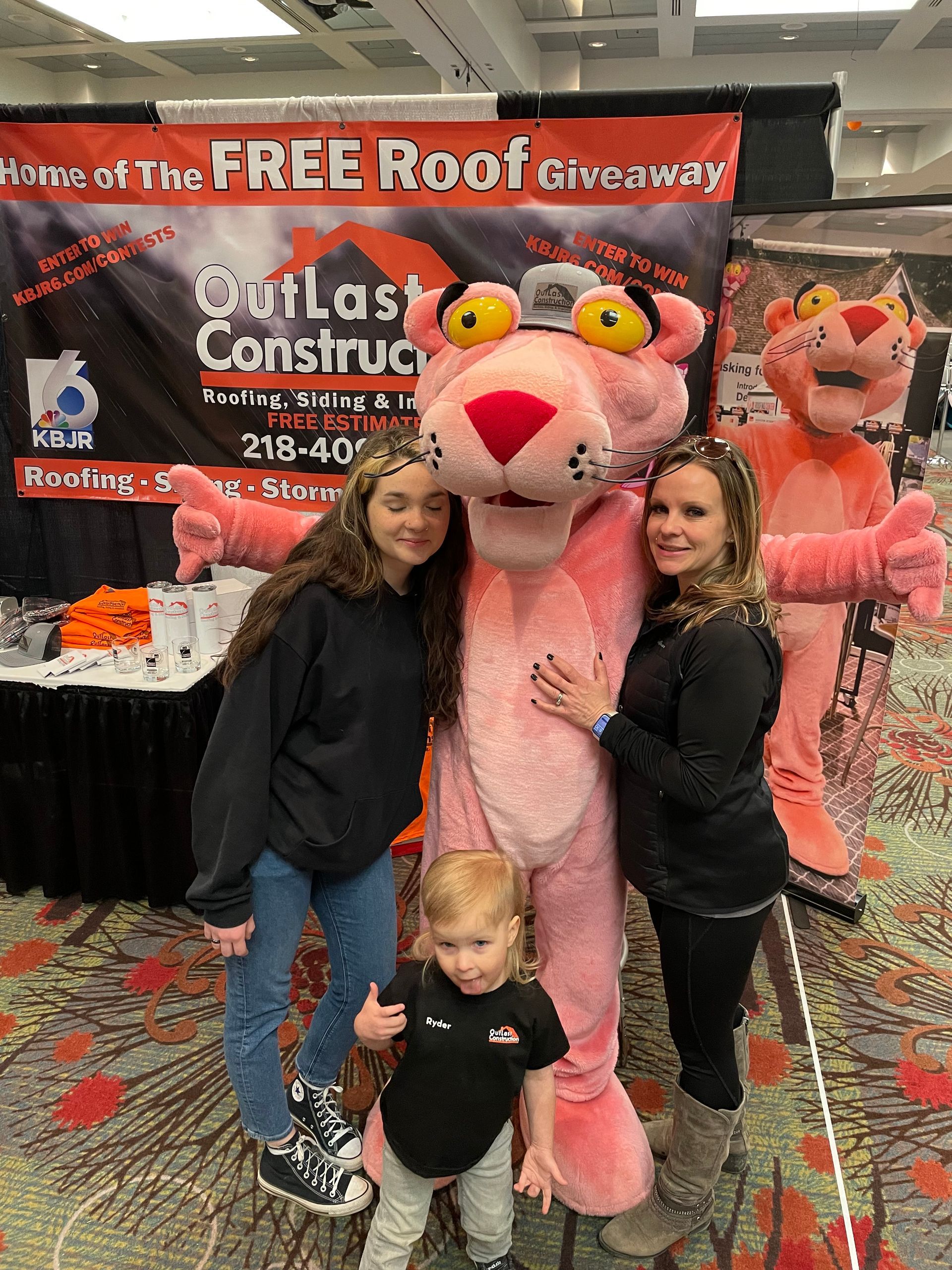 A woman and two children are posing for a picture with a pink panther mascot.