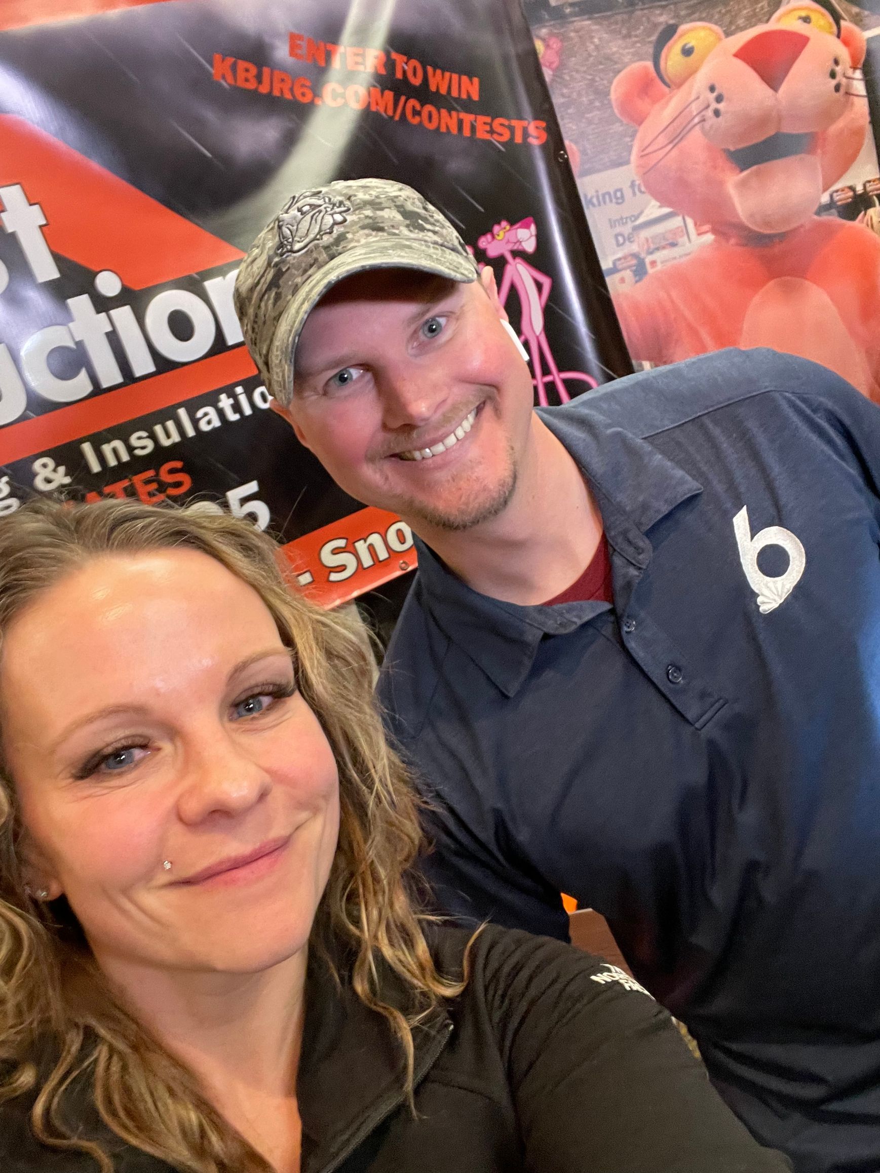 A man and a woman are posing for a picture in front of a pink panther mascot
