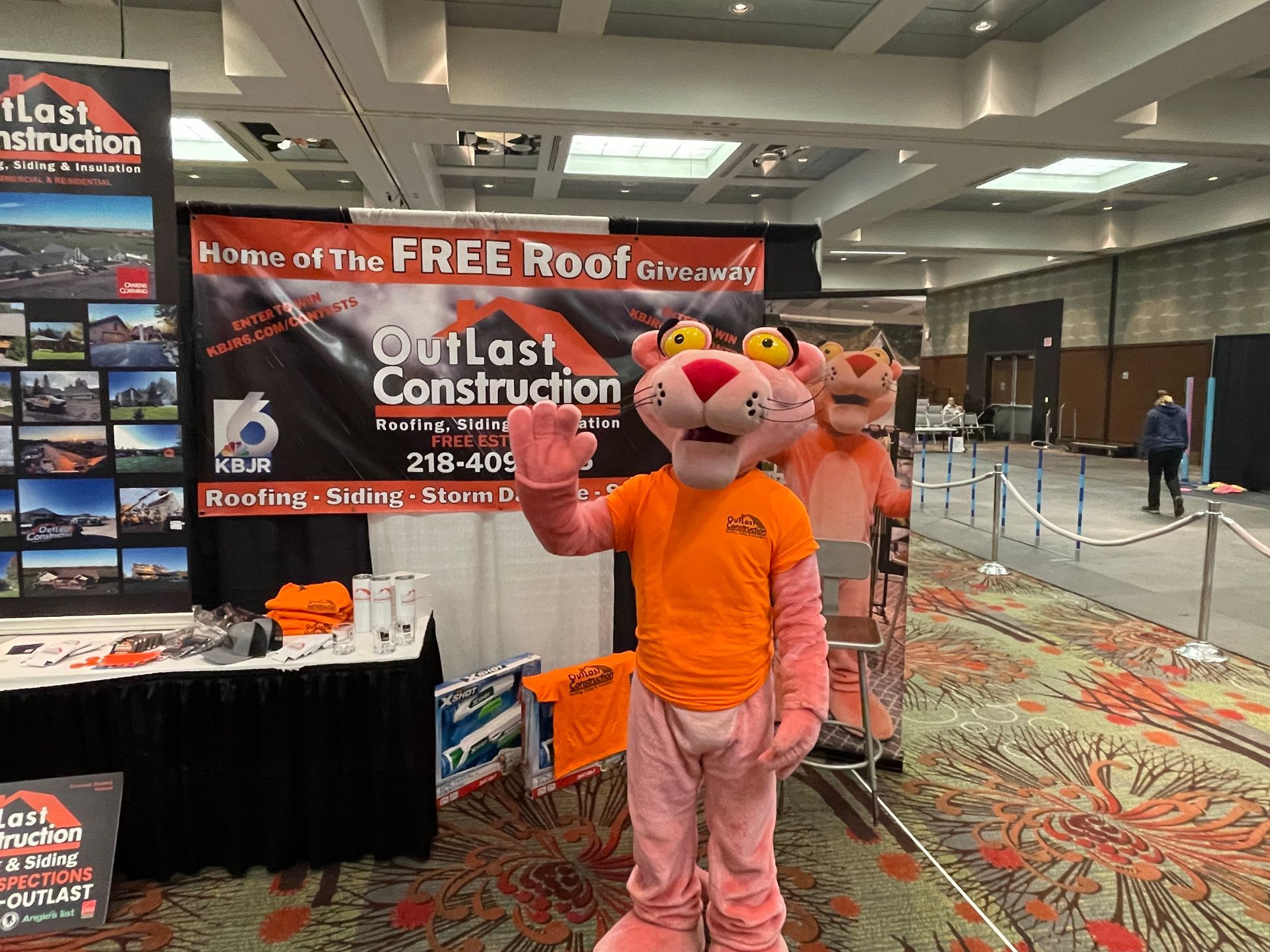 A pink panther mascot is standing in front of a sign for outlast construction