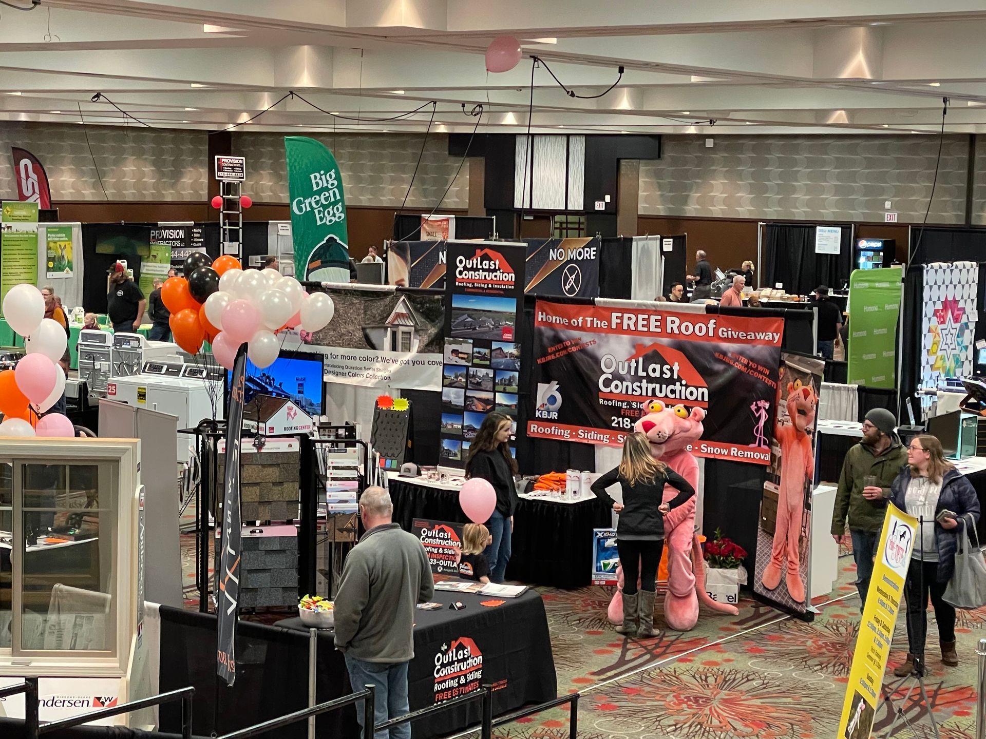 A group of people are standing in a large room at a convention.