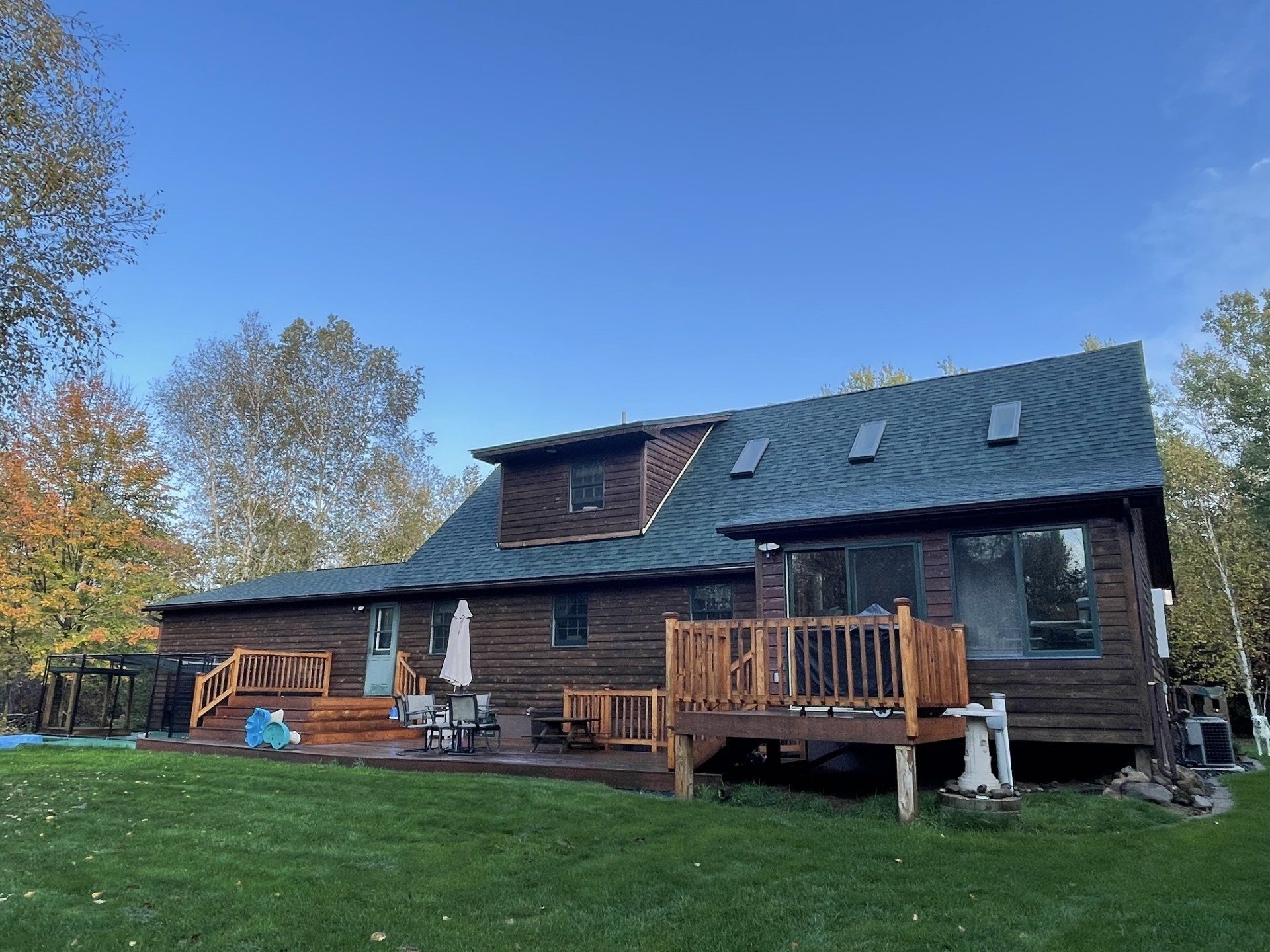 A large log cabin with a green roof and a large deck.